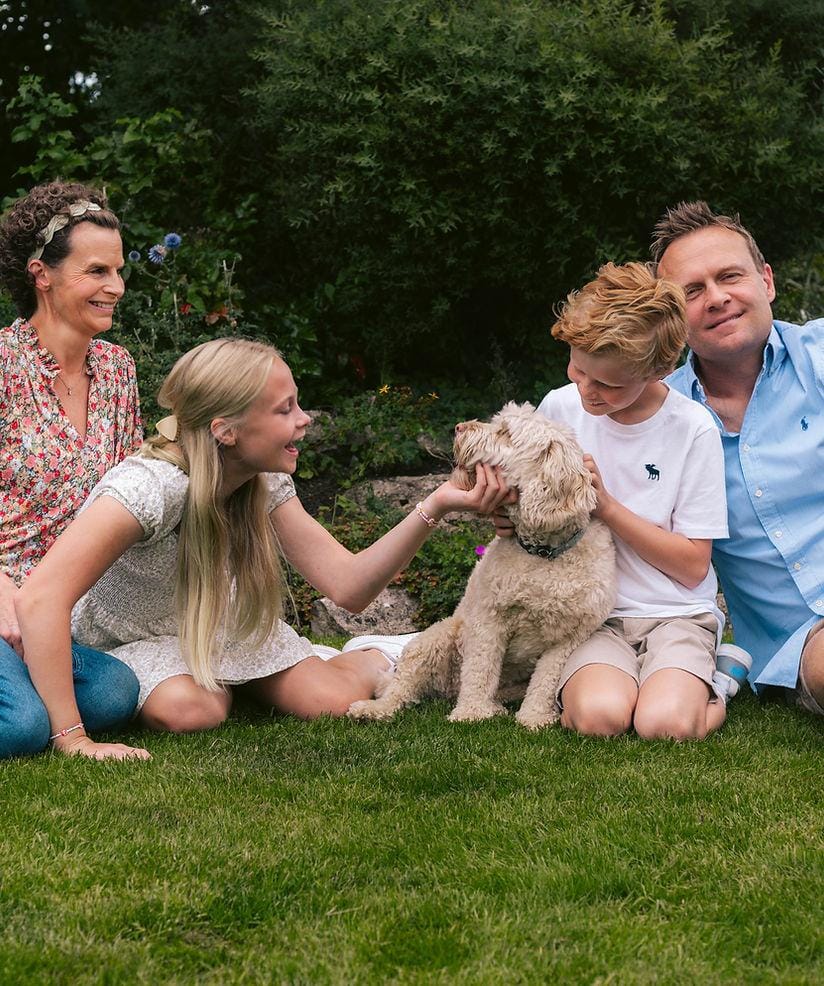 Gastgezin speelt met een Labradoodle in de tuin